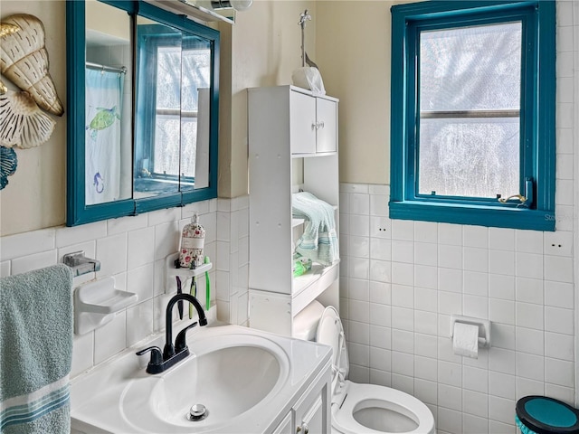 bathroom with vanity, toilet, and tile walls