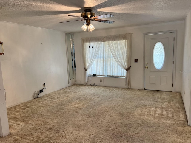 foyer featuring ceiling fan, carpet floors, and a textured ceiling