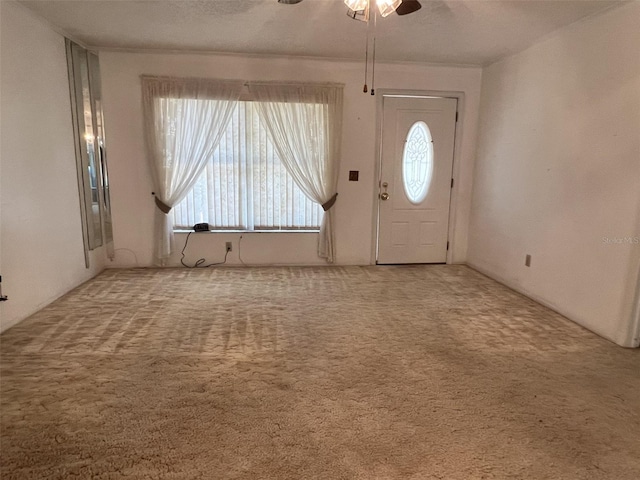 carpeted foyer entrance with crown molding, a healthy amount of sunlight, and ceiling fan