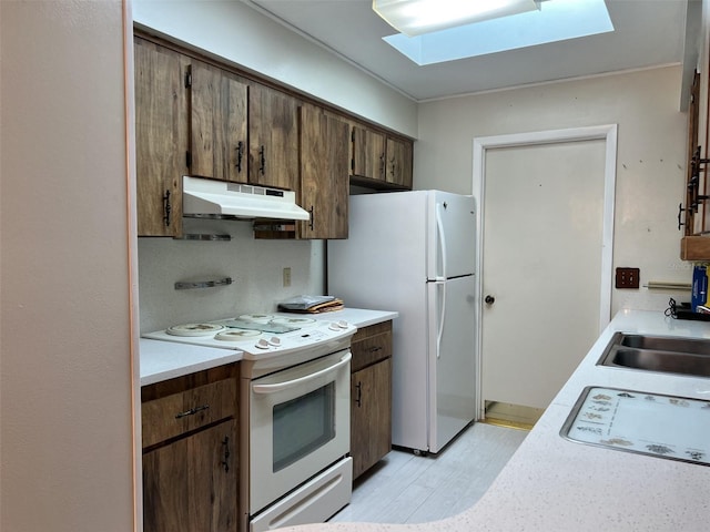 kitchen featuring light hardwood / wood-style floors, white appliances, a skylight, and sink