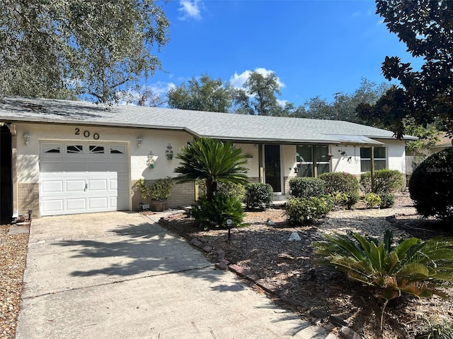 single story home featuring a garage, concrete driveway, and stucco siding