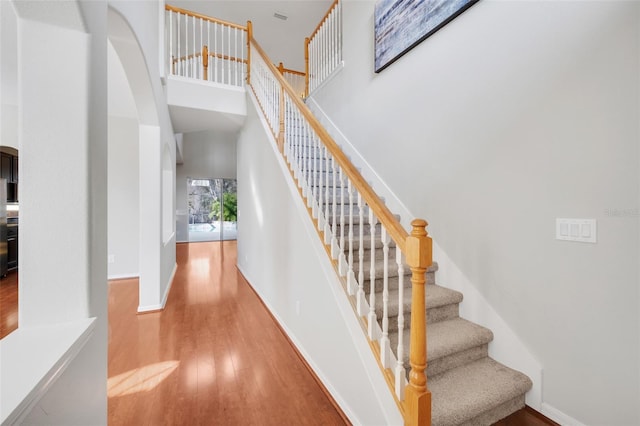 stairs featuring hardwood / wood-style flooring and a towering ceiling