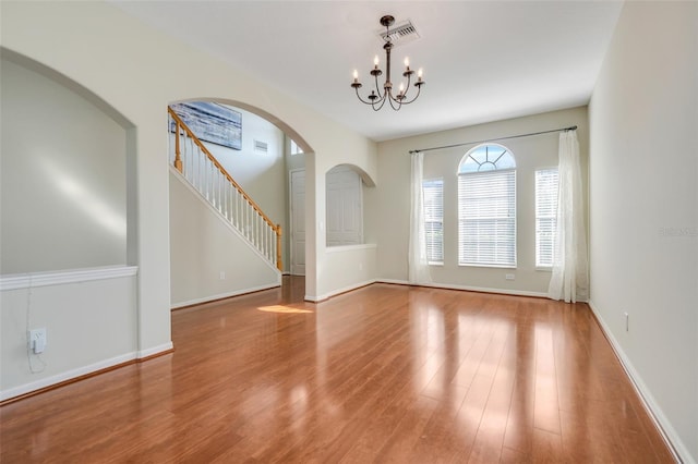 spare room featuring a chandelier and light wood-type flooring