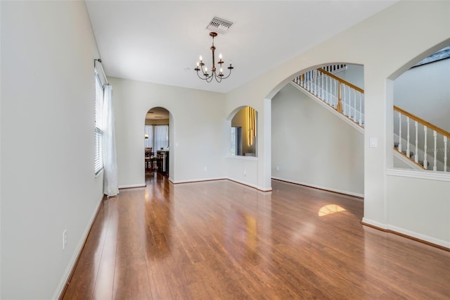 spare room featuring dark hardwood / wood-style floors and a notable chandelier