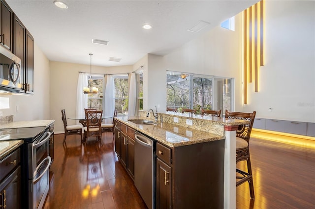 kitchen featuring sink, dark wood-type flooring, a breakfast bar, a kitchen island with sink, and stainless steel appliances