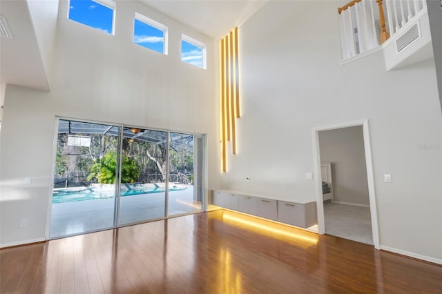 interior space with plenty of natural light, wood-type flooring, and a high ceiling