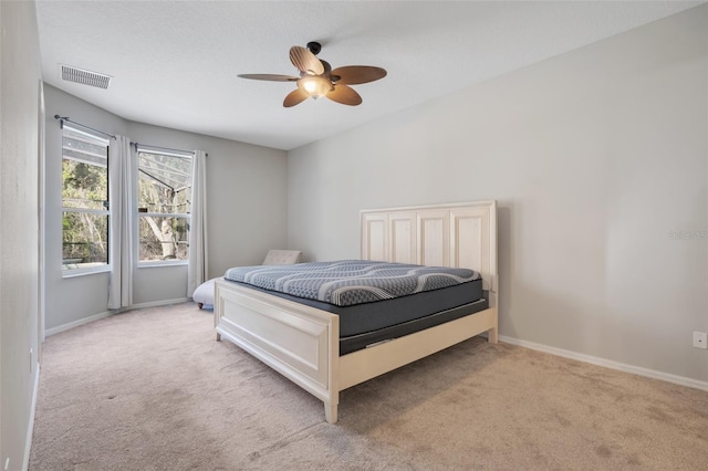 bedroom with ceiling fan, light carpet, and a textured ceiling