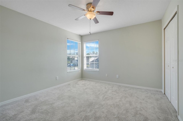 unfurnished bedroom with ceiling fan, light colored carpet, a closet, and a textured ceiling