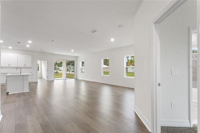 unfurnished living room featuring sink and light hardwood / wood-style flooring