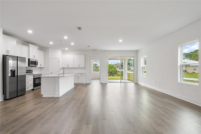 kitchen featuring light hardwood / wood-style flooring, a center island with sink, white cabinets, and appliances with stainless steel finishes