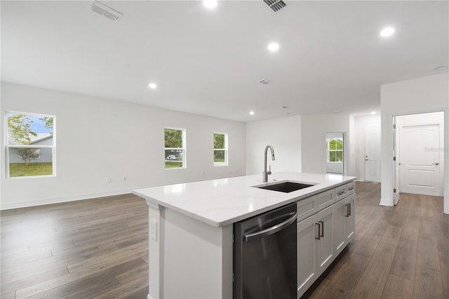 kitchen featuring sink, white cabinets, stainless steel dishwasher, light stone counters, and a center island with sink