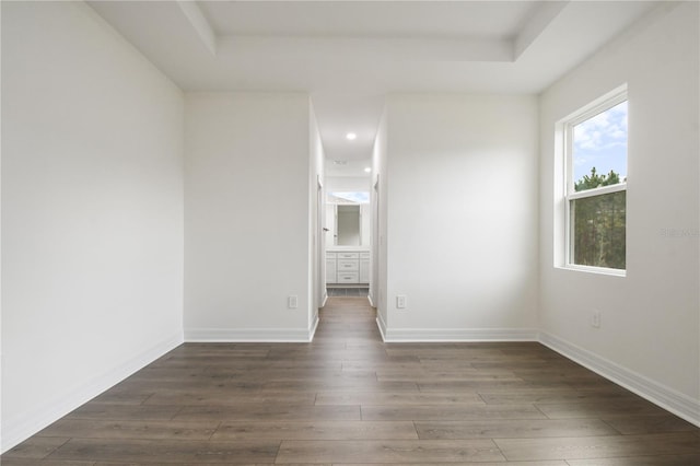 spare room with dark wood-type flooring and a tray ceiling