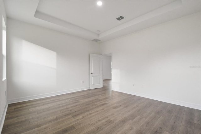 unfurnished room with wood-type flooring and a raised ceiling