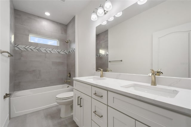 full bathroom featuring tiled shower / bath, vanity, and toilet