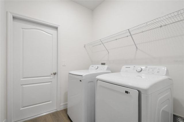 laundry room featuring wood-type flooring and separate washer and dryer