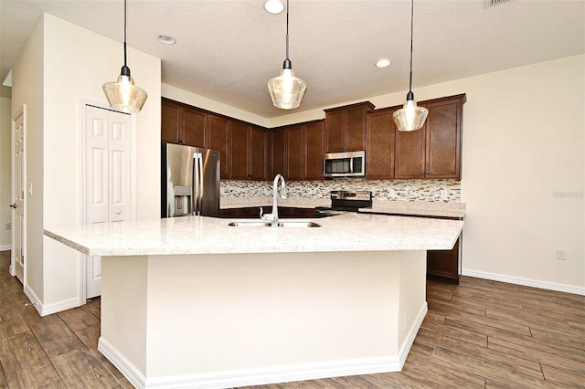 kitchen featuring light stone counters, decorative light fixtures, stainless steel appliances, and dark hardwood / wood-style floors