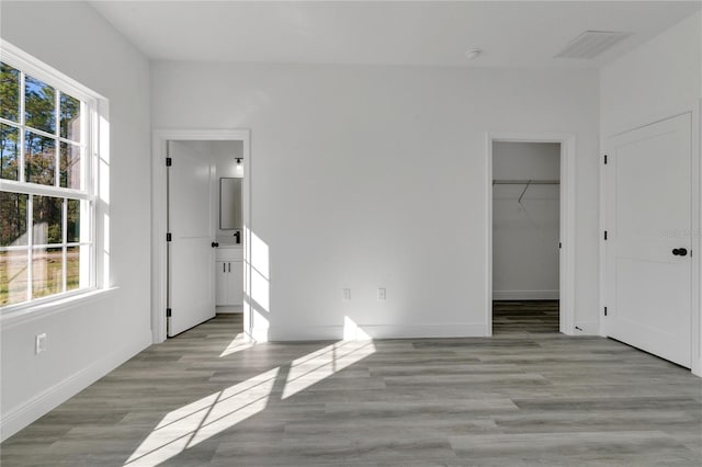 unfurnished bedroom featuring a walk in closet, a closet, and light wood-type flooring