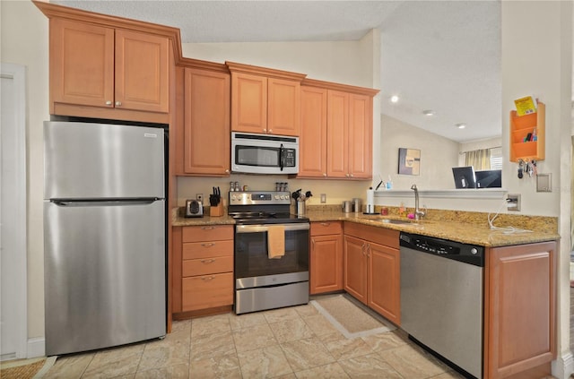 kitchen featuring lofted ceiling, sink, light stone countertops, and appliances with stainless steel finishes