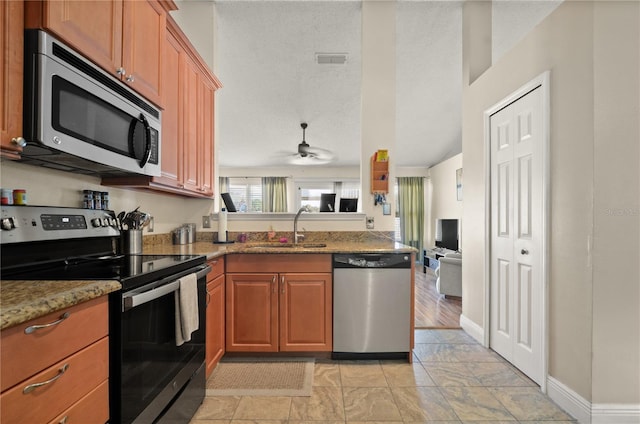 kitchen featuring sink, a textured ceiling, ceiling fan, stainless steel appliances, and light stone countertops