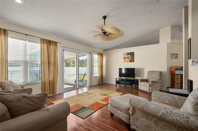 living room with ceiling fan, lofted ceiling, hardwood / wood-style floors, and a textured ceiling