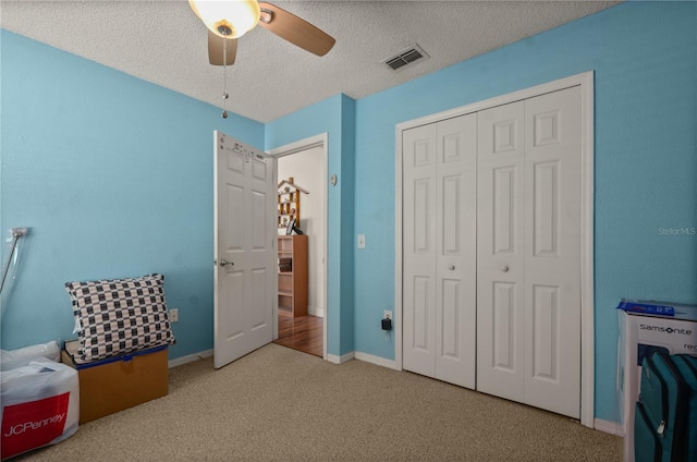 bedroom with ceiling fan, a closet, carpet flooring, and a textured ceiling