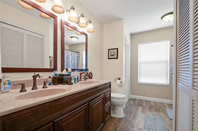 bathroom with a healthy amount of sunlight, wood-type flooring, toilet, and vanity