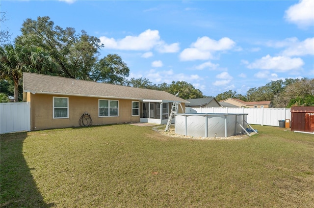 rear view of house featuring a fenced in pool, a sunroom, and a lawn