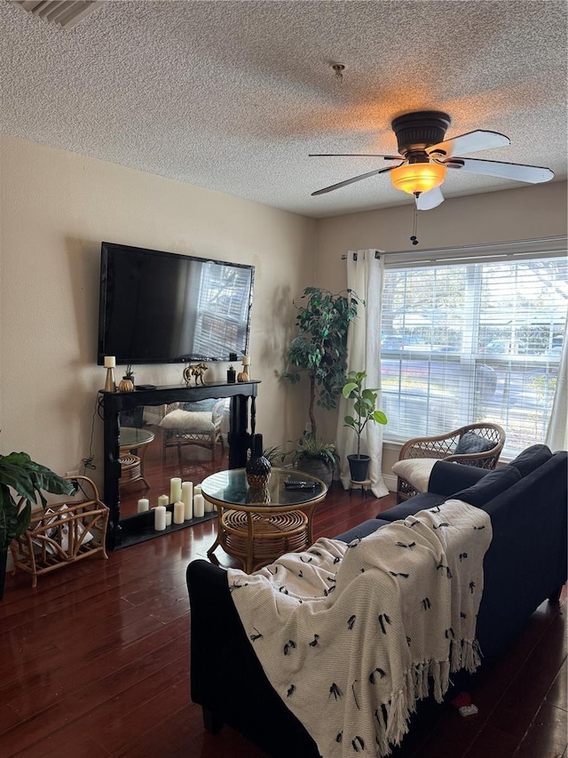 living room featuring ceiling fan, dark hardwood / wood-style floors, and a textured ceiling