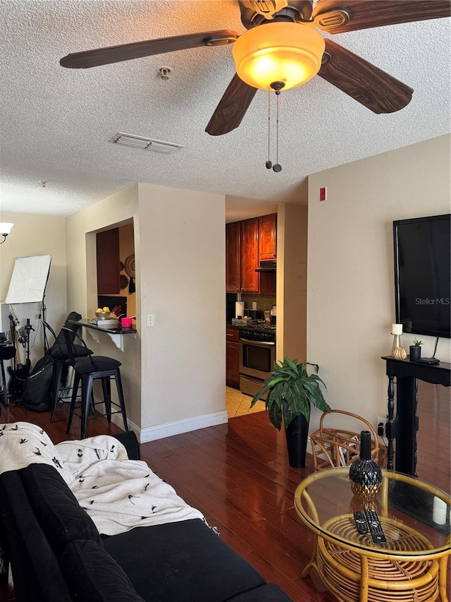 living room with dark hardwood / wood-style flooring, a textured ceiling, and ceiling fan