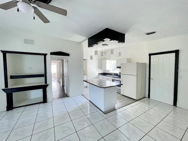 kitchen with sink, white cabinetry, a kitchen island, white fridge, and pendant lighting