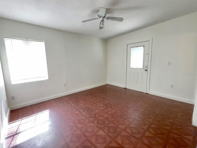 unfurnished room with ceiling fan and dark parquet floors