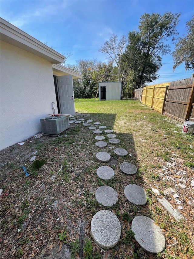 view of yard featuring a storage unit and central AC unit