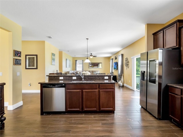 kitchen with sink, a center island with sink, dark wood-type flooring, and appliances with stainless steel finishes