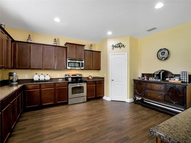 kitchen featuring dark hardwood / wood-style flooring, stainless steel appliances, dark stone countertops, and dark brown cabinetry