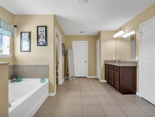 bathroom featuring tile patterned flooring, vanity, toilet, and a tub to relax in