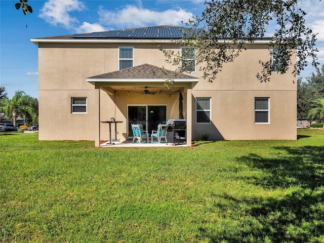 back of house featuring a patio, a lawn, ceiling fan, and solar panels