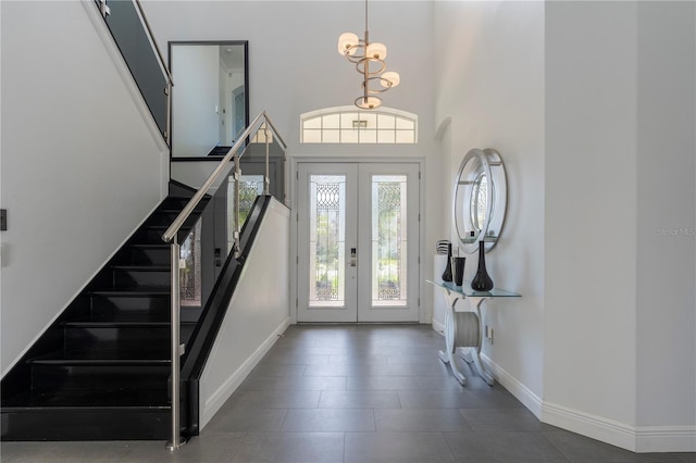 foyer entrance with french doors, a chandelier, and a high ceiling