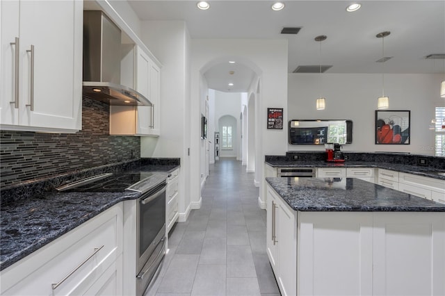 kitchen with pendant lighting, white cabinetry, electric range, and wall chimney range hood