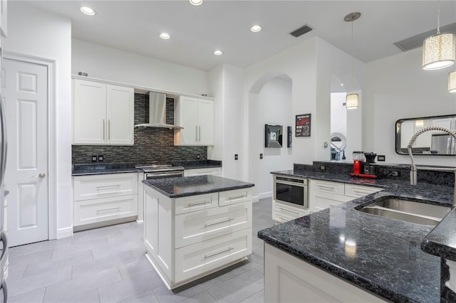 kitchen featuring pendant lighting, wall chimney range hood, sink, white cabinetry, and stainless steel electric range oven