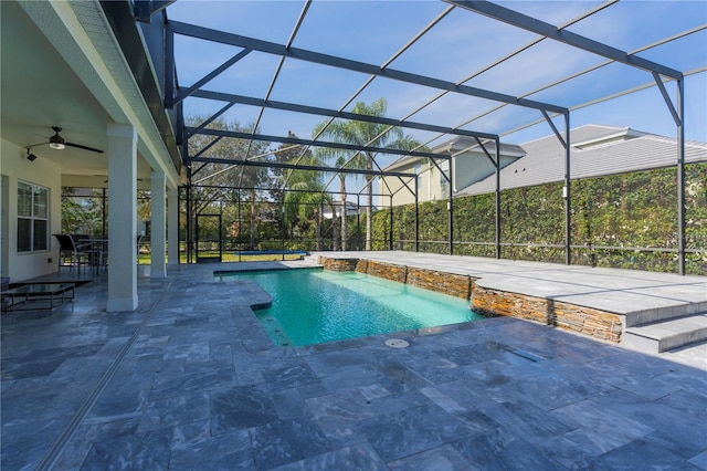 view of swimming pool with a patio area, pool water feature, ceiling fan, and glass enclosure