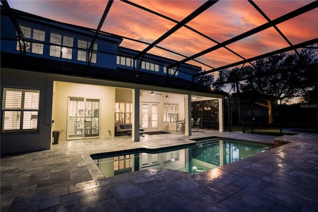 pool at dusk featuring a patio, ceiling fan, and glass enclosure