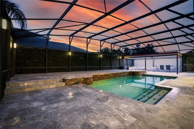 pool at dusk with a lanai and a patio area