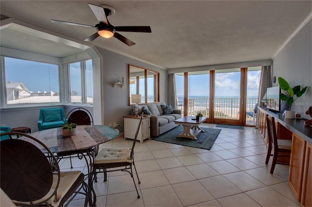 living room with a water view, ceiling fan, ornamental molding, and light tile patterned floors