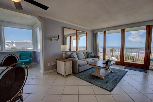 living room featuring light tile patterned flooring, a water view, and ornamental molding