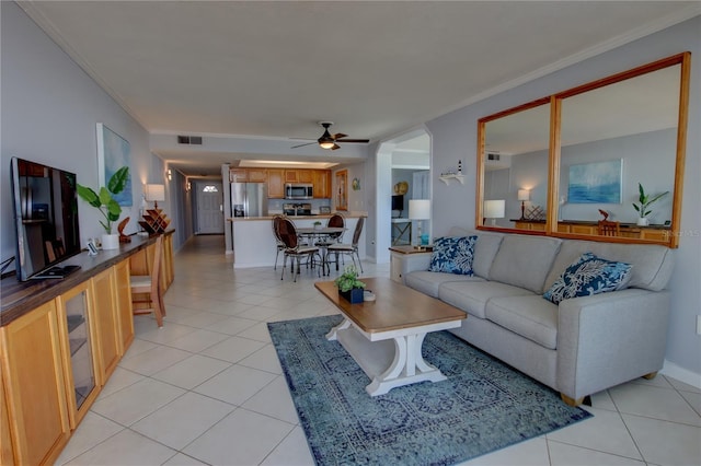 tiled living room with ceiling fan and ornamental molding