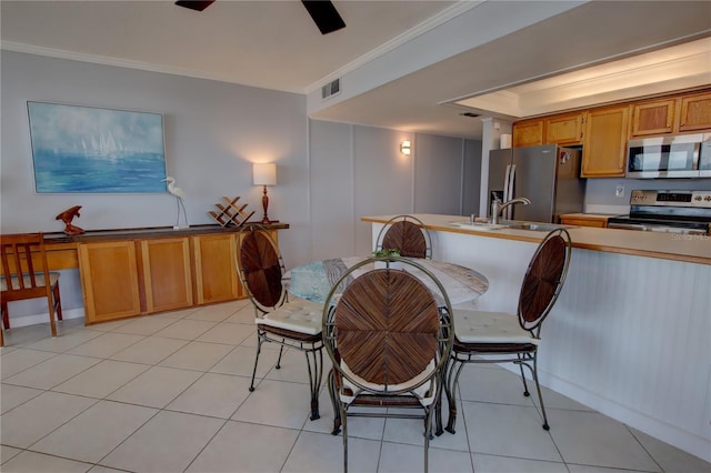 dining room featuring ornamental molding, sink, and light tile patterned floors