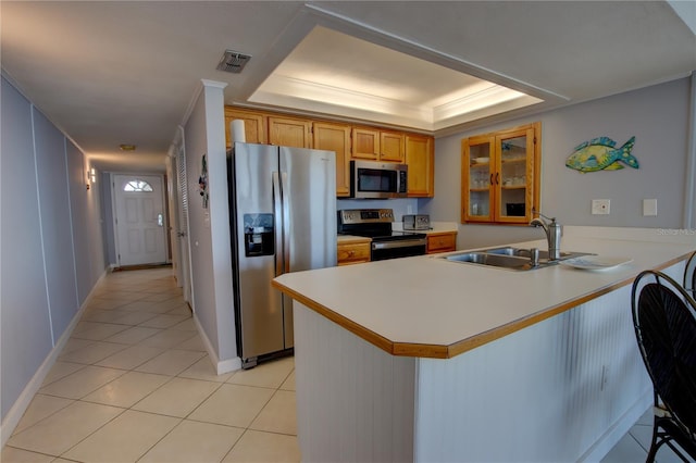 kitchen with sink, light tile patterned floors, a raised ceiling, kitchen peninsula, and stainless steel appliances