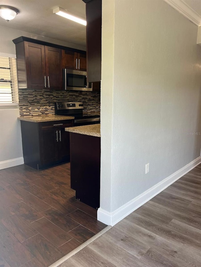 1315 Carlsbad Pl, Orlando, FL 32808 - kitchen with dark wood-type flooring, appliances with stainless steel finishes, dark brown cabinetry, light stone countertops, and decorative backsplash
