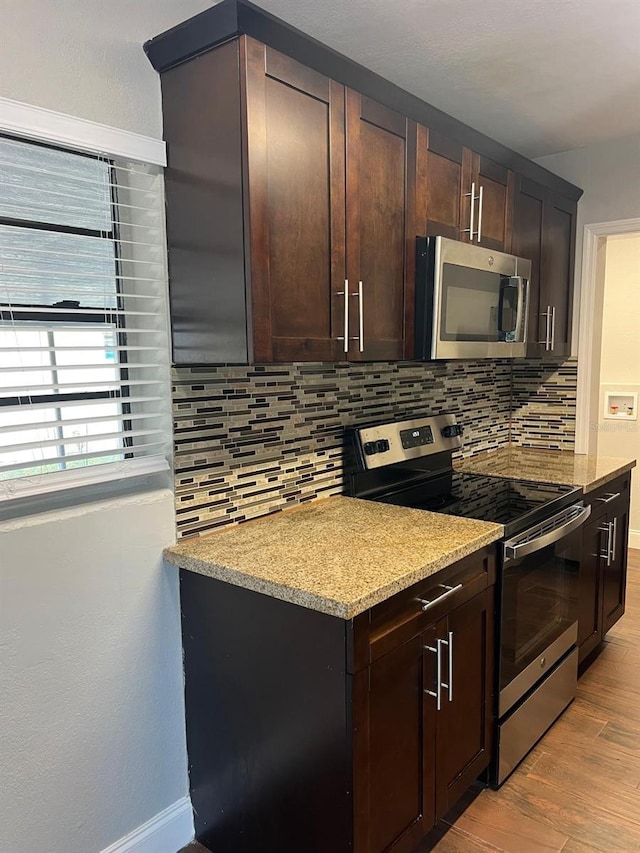 1315 Carlsbad Pl, Orlando, FL 32808 - kitchen featuring appliances with stainless steel finishes, backsplash, light stone counters, light hardwood / wood-style floors, and dark brown cabinets