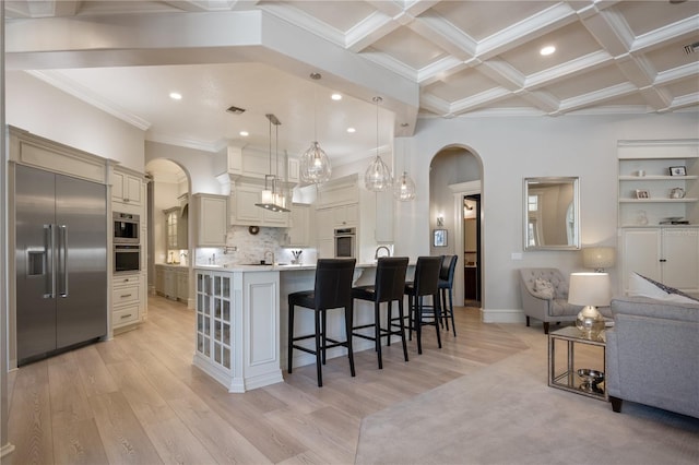 kitchen featuring pendant lighting, cream cabinetry, built in fridge, and a spacious island